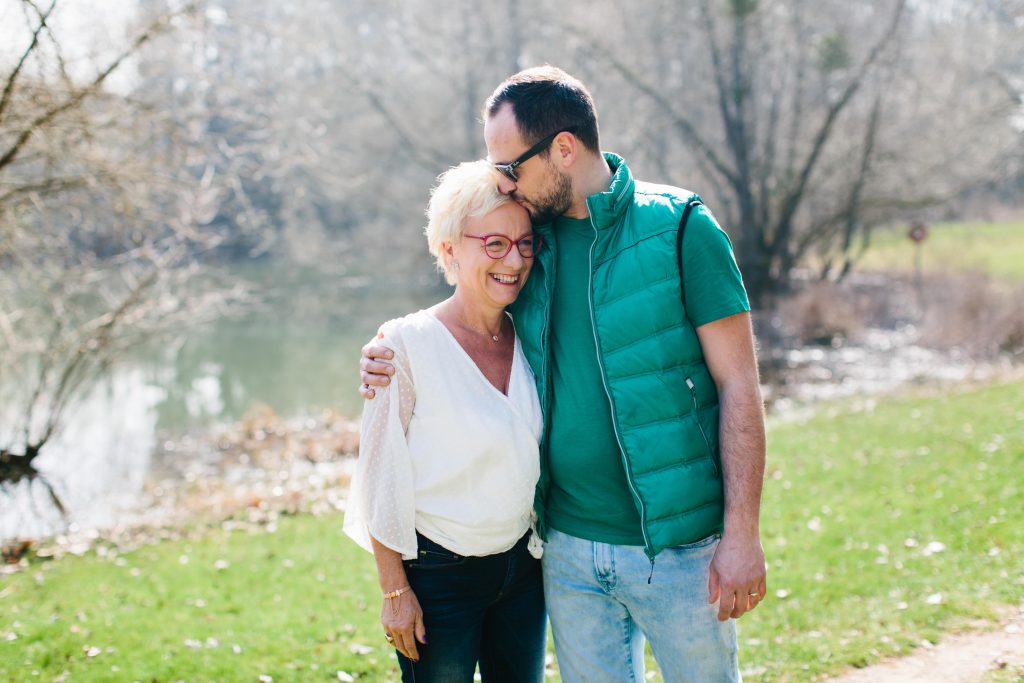 Photographie d'une maman et de son grand fils qu'il embrasse sur le front