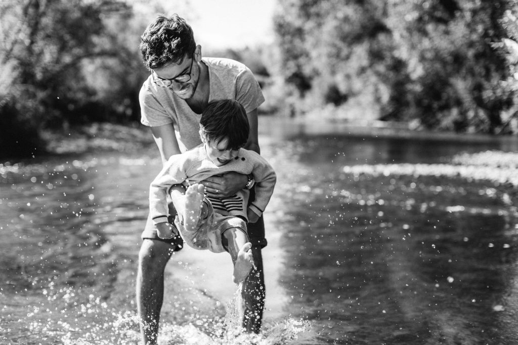Portrait d'un petit garçon et son papa jouant dans une rivière