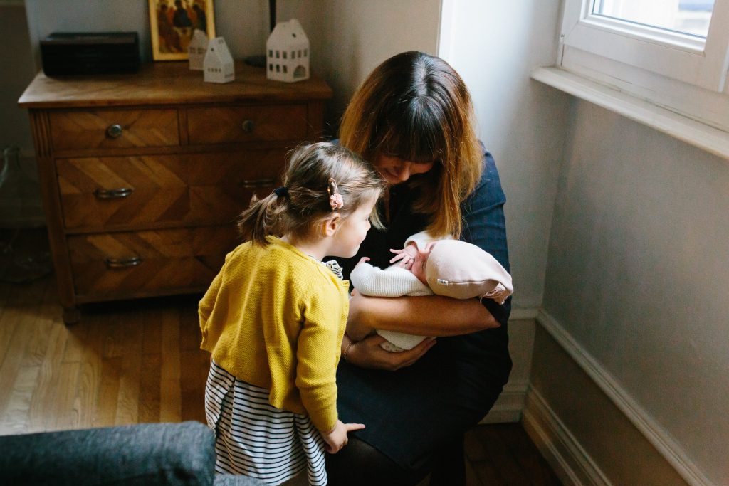 Photo d'une grande sœur qui fait connaissance avec son petit frère nouveau-né