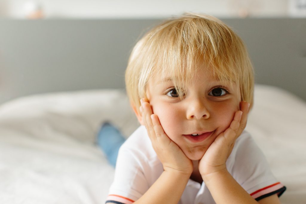Petit garçon aux yeux marrons qui entoure son visage de ses mains