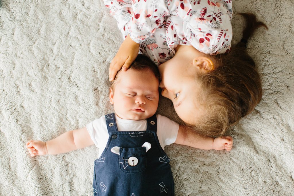 Grande sœur faisant un bisou sur le front de son petit frère nouveau-né