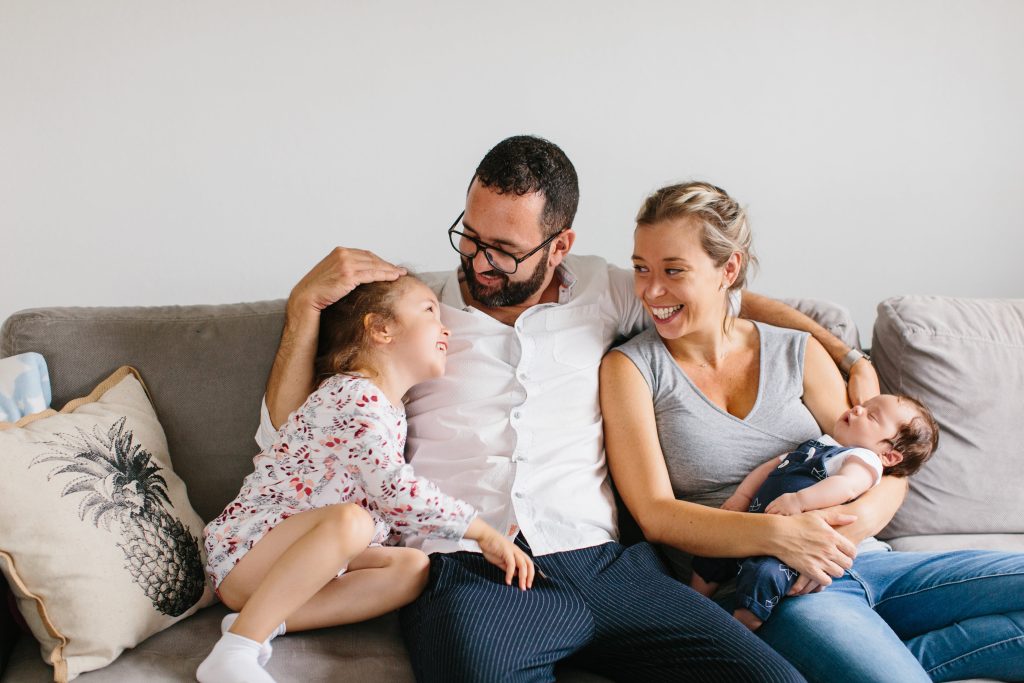 Photo de famille prise suite à la naissance d'un bébé avec la grande sœur, assis sur un canapé