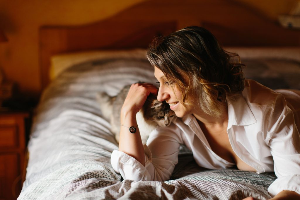 Portrait intime d'une femme allongée sur le lit qui caline son chat